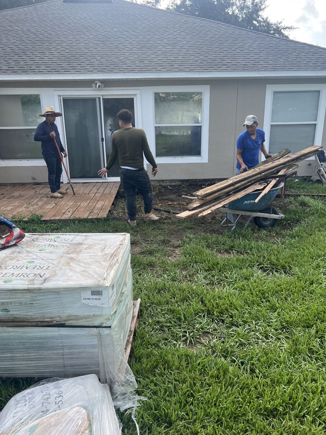 Old deck being removed with pallets of pavers delivered to the job site